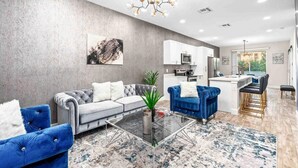 Un salon moderne avec un canapé gris, un fauteuil bleu et une table basse en verre.