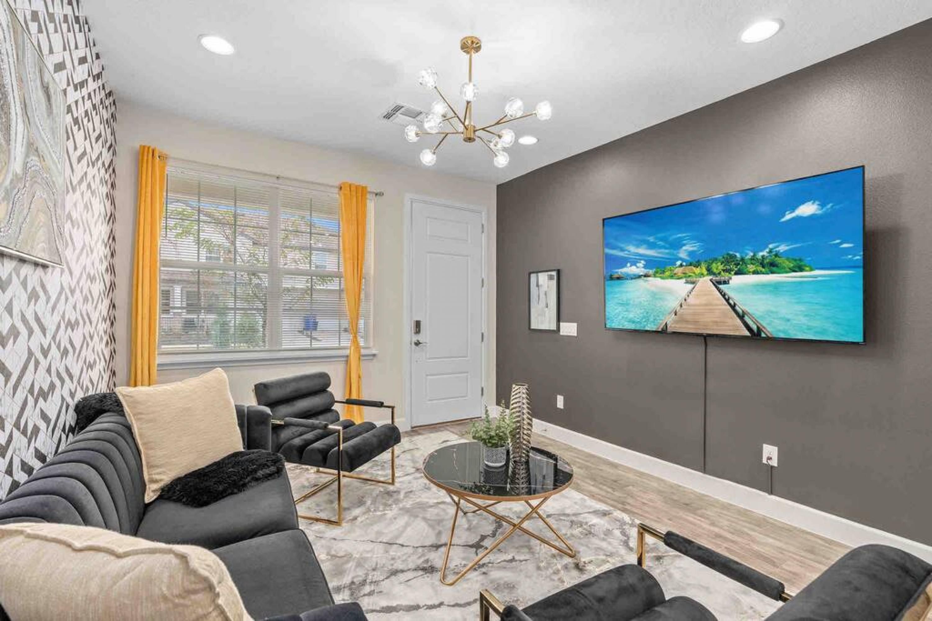 A modern living room with a large flat-screen TV, a sofa set, a coffee table, and a patterned wall.