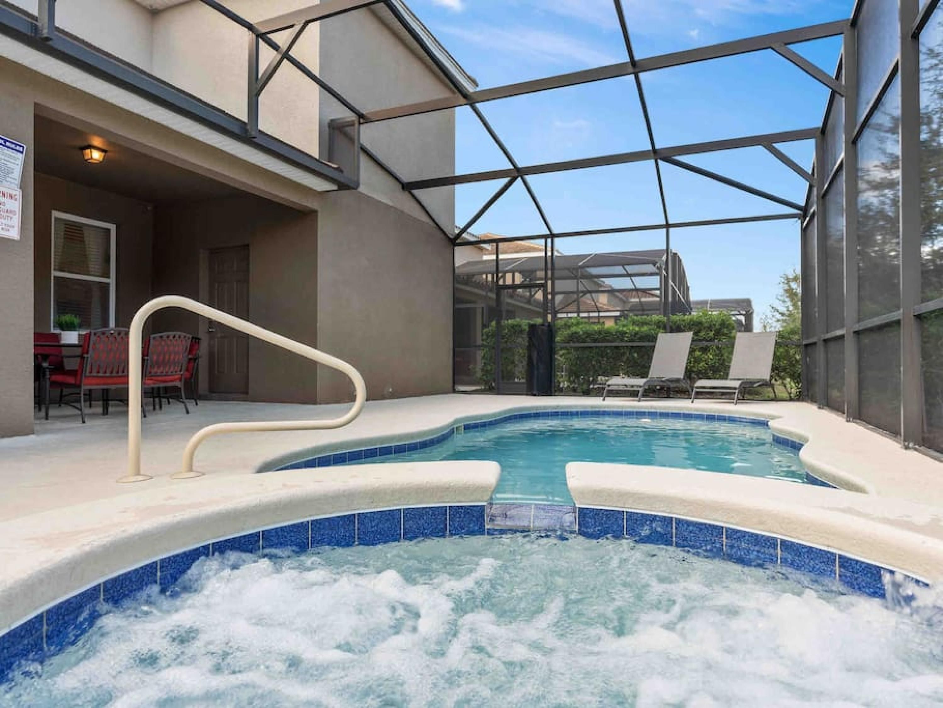 Un bain à remous doté d’une enceinte en verre, un espace patio avec des chaises et une vue sur l’extérieur.