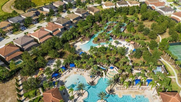 Vista aérea de un resort con múltiples piscinas, palmeras y edificios residenciales.