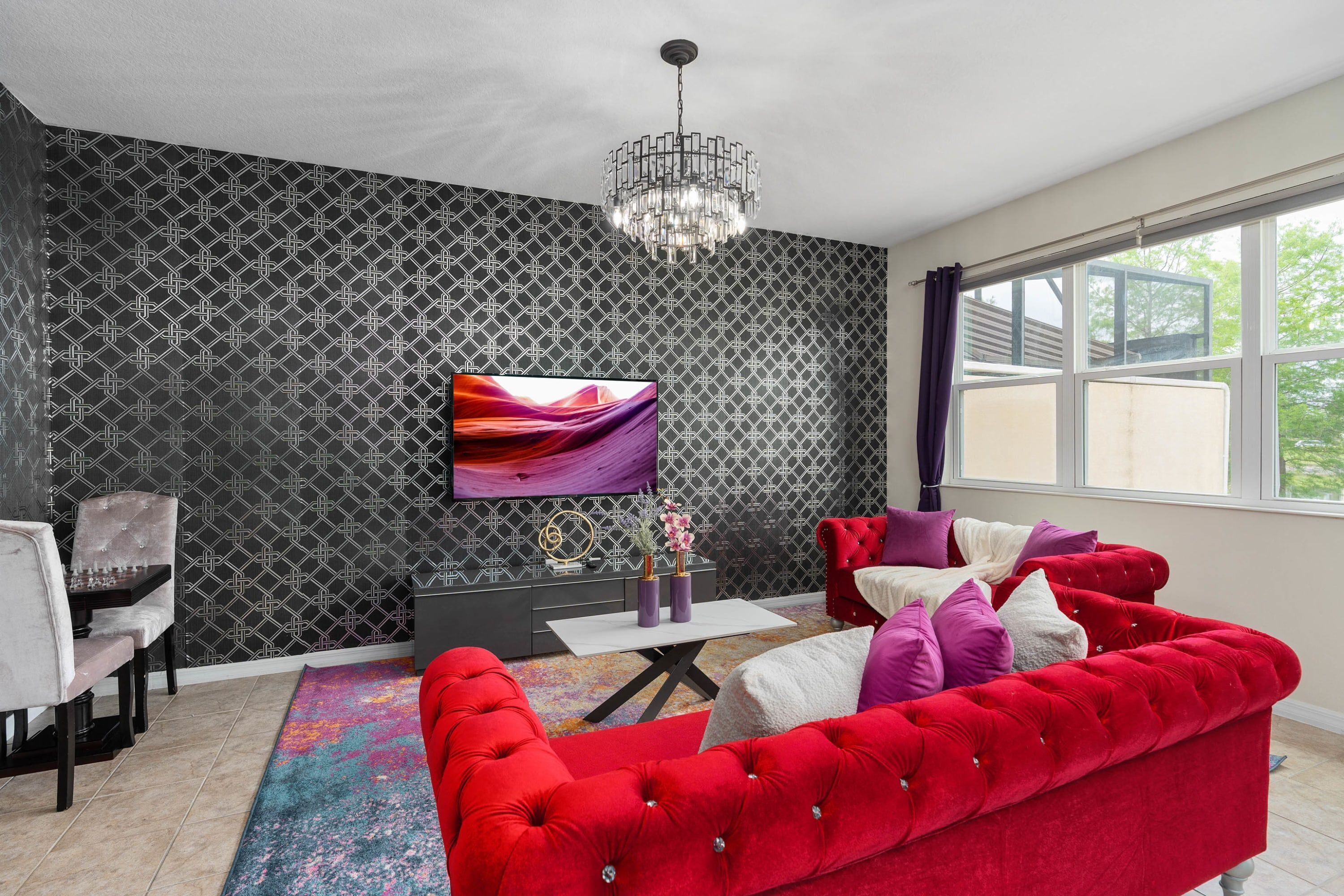 A modern living room with a red sofa, a TV mounted on the wall, and a patterned wallpaper.