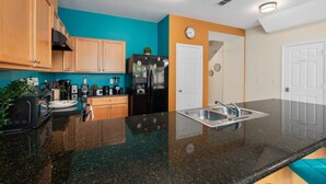 Una cocina moderna con armarios de madera, un refrigerador negro, un lavamanos y un reloj en la pared.