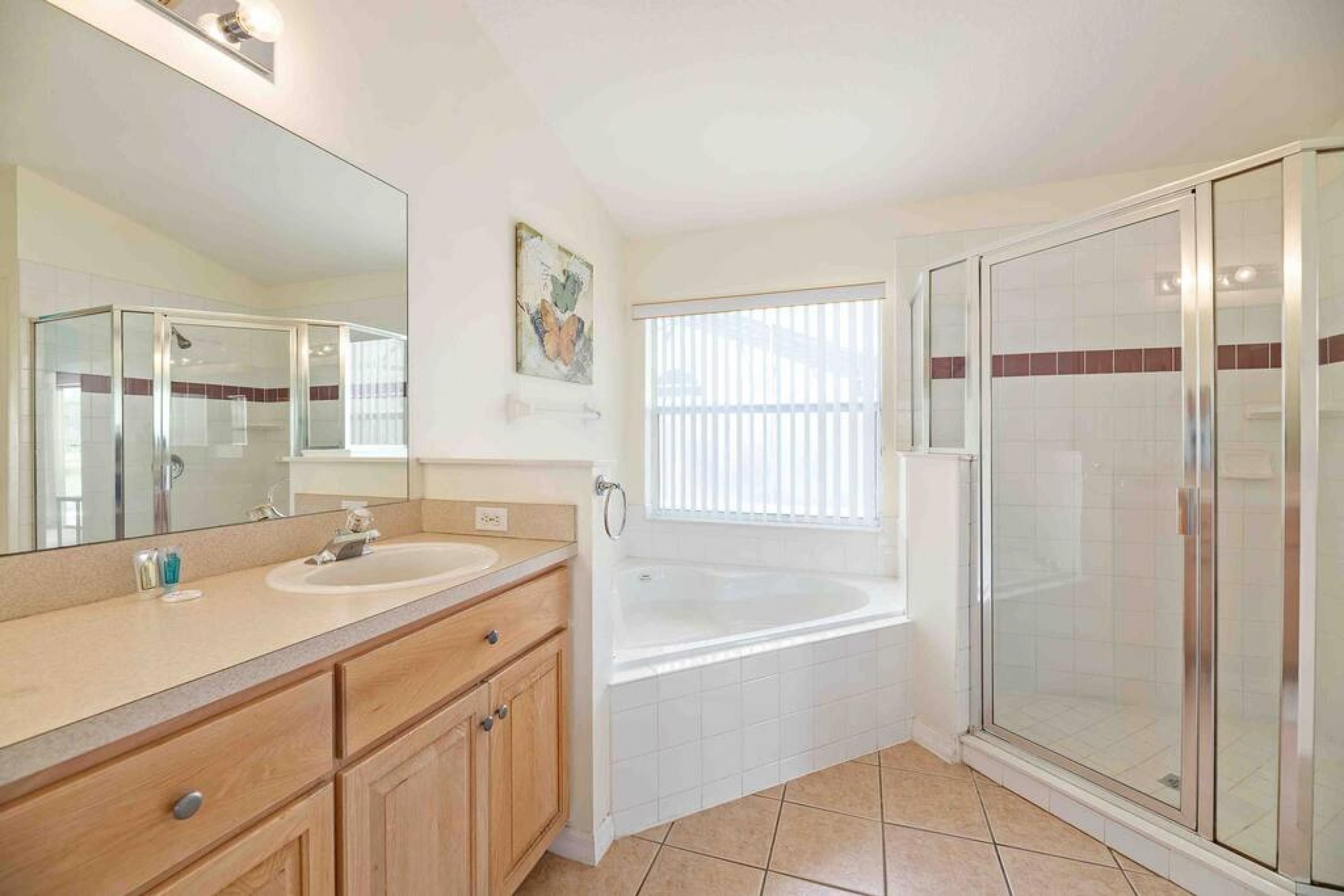A modern bathroom with a glass-enclosed shower, a bathtub, and a vanity with a mirror.