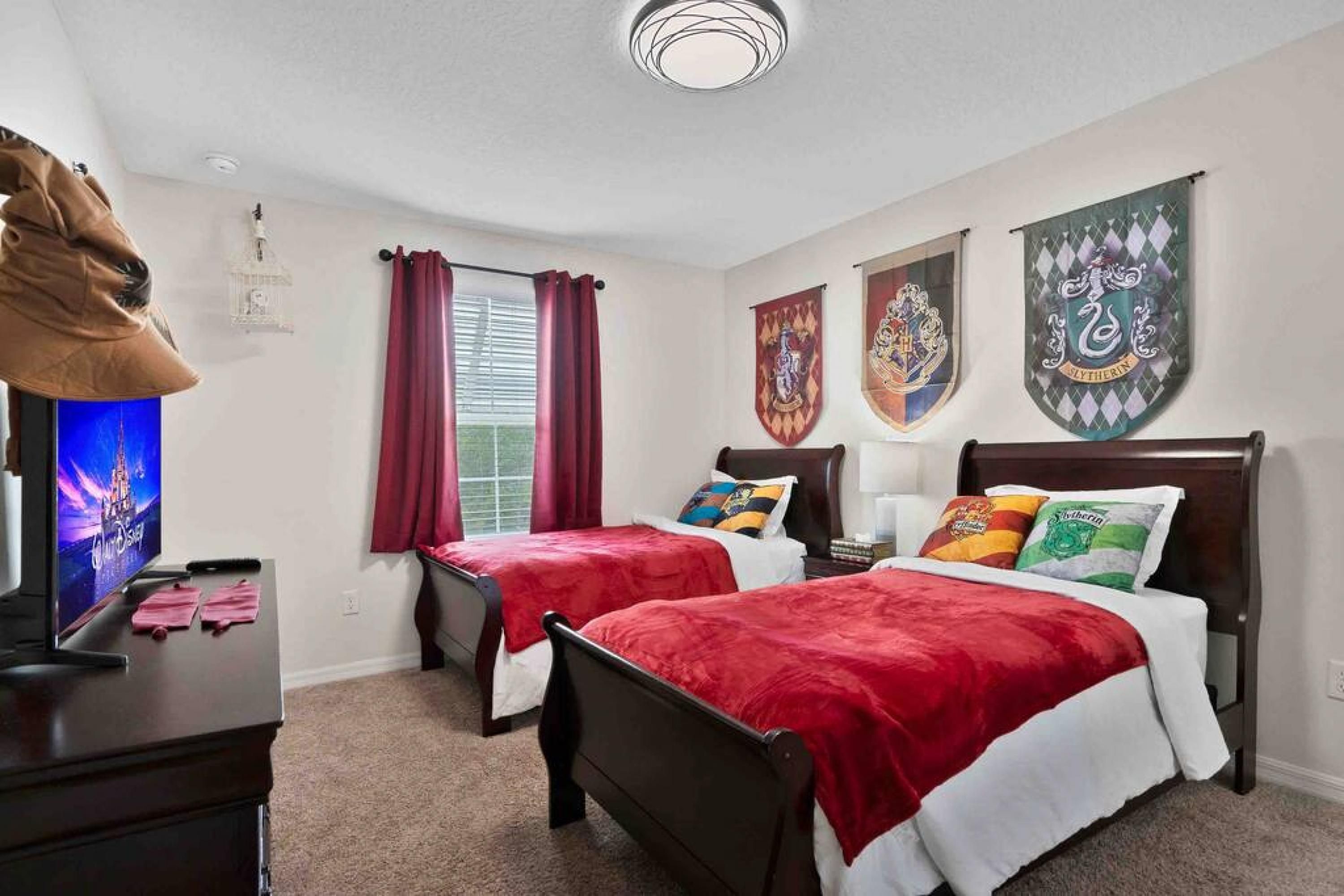 Quarto de hotel com duas camas, televisão e janela com cortinas.