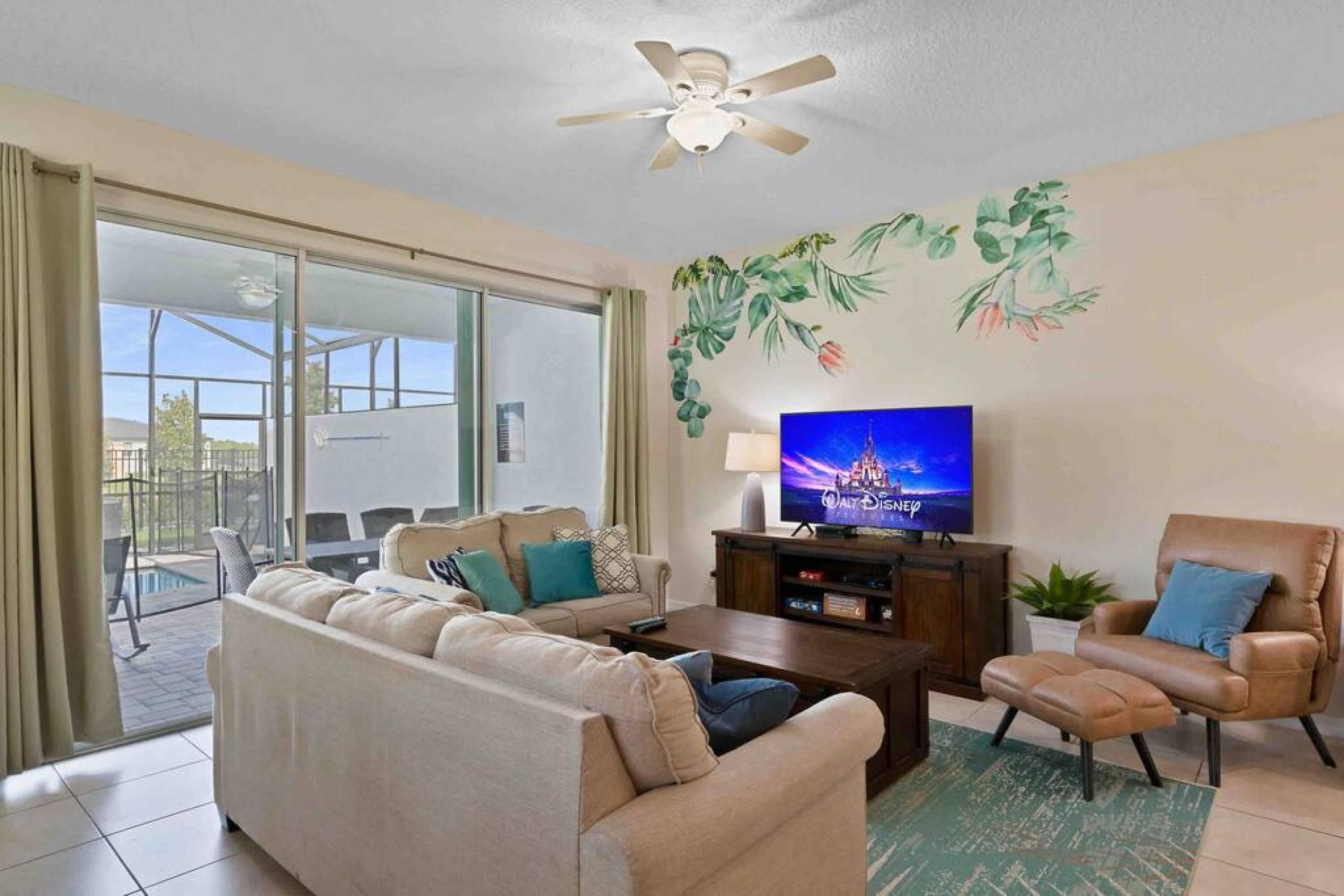 A living room with a sofa, armchair, coffee table, TV, and a ceiling fan.