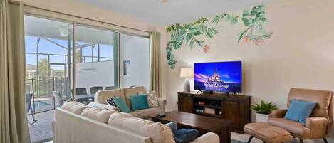 A living room with a sofa, armchair, coffee table, TV, and a ceiling fan.