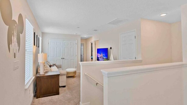 A hallway with a white door, a small seating area with a lamp, and a wall-mounted artwork. - Super Snug- FUN Themes Pool Tons OF Amenities (Kissimmee)