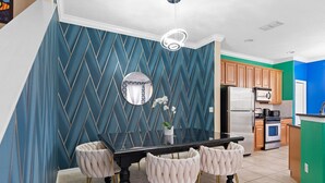 Una cocina moderna con comedor, que incluye una mesa negra, sillas blancas y un espejo decorativo.