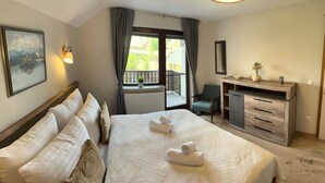 A hotel room with a bed, a desk, a chair, a window with a view, and a painting on the wall. - Vila Minka - Your Perfect Bled Getaway (Bled)