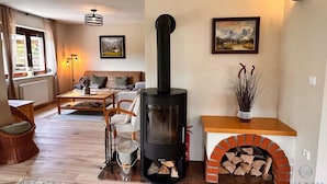 A cozy living room with a wood-burning stove, a sofa, a dining table, and a fireplace. - Vila Minka - Your Perfect Bled Getaway (Bled)