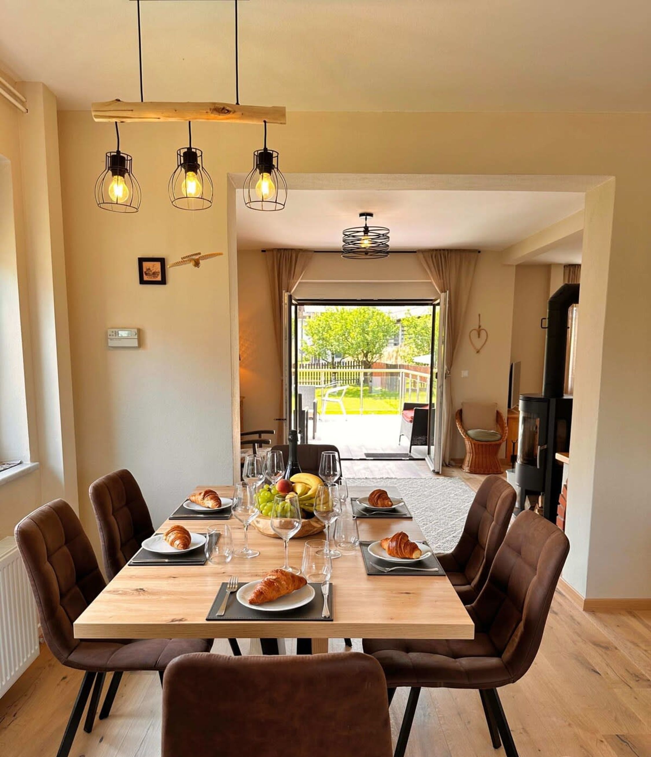 Een eetgedeelte met een houten tafel, beklede bruine stoelen en hangende吊灯.