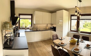 Une cuisine moderne avec des meubles blancs, un plan de travail noir et un coin repas avec une table dressée pour deux personnes.