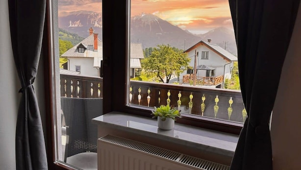 A room with a view of a mountain range and houses during sunset. - Vila Minka - Your Perfect Bled Getaway (Bled)