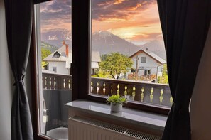 A room with a view of a mountain range and houses during sunset. - Vila Minka - Your Perfect Bled Getaway (Bled)