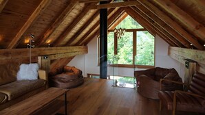 Een kamer met hoge houten plafonds, een groot raam, leren banken en een houten bank.