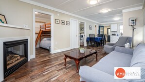 A spacious living room with hardwood flooring, a fireplace, a sofa, a dining area, and a staircase leading to another level. - Rest and Relaxation Z s at Slayton Lake (Belding)