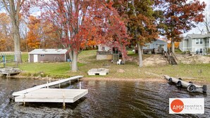 A lakeside property with a dock, a small shed, and a house with a deck. - Rest and Relaxation Z s at Slayton Lake (Belding)
