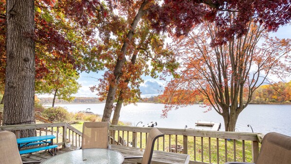 A deck with outdoor seating, overlooking a lake with autumn foliage. - Rest and Relaxation Z s at Slayton Lake (Belding)