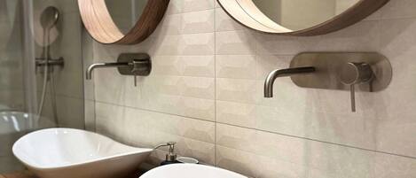 A bathroom with two white vessel sinks, wooden countertop, and two round mirrors with wooden frames.