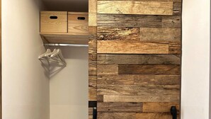 A closet with a wooden slat wall design, a bench, and hanging clothes.