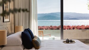 A hotel room with a bed, a bedside table with a lamp, a tray with tea set, and a view of the sea and mountains. - Syrah 3-bedroom Beachfront Villa in Koh Samui (Koh Samui)