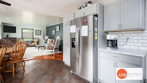 Una cocina moderna con armarios grises, un refrigerador de acero inoxidable y una cafetera en la encimera.