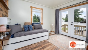 Un dormitorio acogedor con cama, mesita de noche, lámpara, ventana y puerta corrediza de vidrio que da a una terraza exterior.