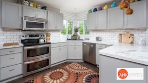 Una cocina moderna con armarios blancos, electrodomésticos de acero inoxidable y un tapete estampado.