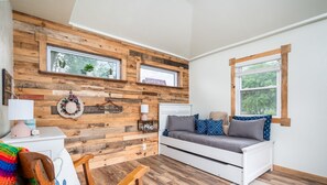 A cozy room with a wooden wall, a white sofa, a wooden chair, and a small table with a lamp. - 1 Happy Acre in Holland (Holland)