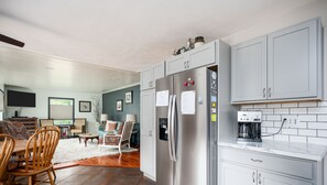 Une cuisine moderne avec des meubles gris, un réfrigérateur en acier inoxydable et une machine à café posée sur le plan de travail.