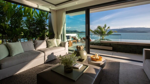 Una sala de estar moderna con sofá, mesa de centro y vista al mar.