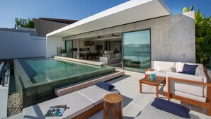 Una casa moderna con piscina, mobiliario exterior y un amplio ventanal que da al interior.