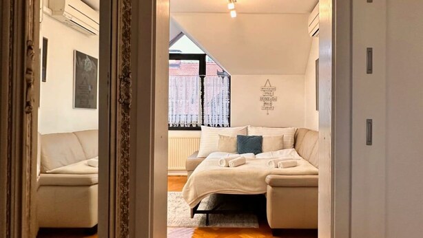 A bedroom with a bed, a mirror, and a view of the outside. - Charming City Loft Apartment With Free Parking (Ljubljana)