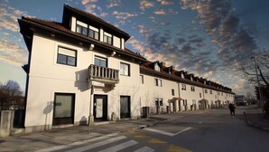 A row of white buildings with balconies, a pedestrian crossing, and a clear sky. - Charming City Loft Apartment With Free Parking (Ljubljana)