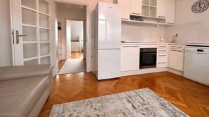 A compact kitchen with white cabinets, a refrigerator, an oven, and a dishwasher. - Charming City Loft Apartment With Free Parking (Ljubljana)