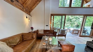 Ein großzügiges Wohnzimmer mit einer Ledersofa, einem Glastisch und Holzboden.