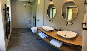 Une salle de bain moderne dotée d’une douche à parois de verre, d’un meuble-lavabo en bois avec deux vasques et de deux miroirs fixés au mur.