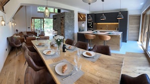 Ein moderner Essbereich mit einem langen Holztisch, gedeckt für eine Mahlzeit, umgeben von Ledersesseln.