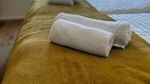 A hotel room with a bed, a window, and two towels on a brown bedspread. - Garden Residence - Premium Downtown Apartment (Ljubljana)