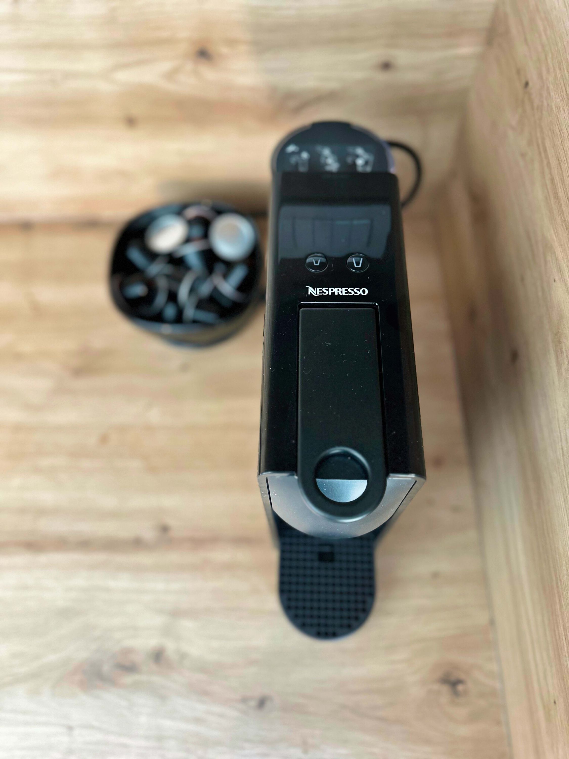 Een zwarte Nespresso koffiemachine in een houten doos.