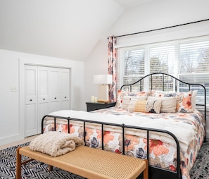 A bedroom with a bed, bedside table, lamp, and a bench. - Downtown Douglas Coach House (Douglas)