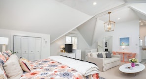Ein Schlafzimmer mit Bett, Schreibtisch, Sofa und Essbereich.