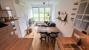 A modern kitchen with wooden countertops, a dining area with a table and chairs, a built-in oven, and a large window with a view of greenery. - So a Valley Suites - Superior Apartment 09 (Bovec)