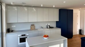 Eine moderne Küche mit weißen Schränken, einem Backofen, einer Spüle und einer Arbeitsfläche mit einer Obstschale.
