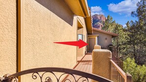 A hotel entrance with a metal gate, a beige exterior wall, and a view of a mountain in the background. - Mammoth Rock Oasis-1 bd 1ba Hot Tub Free Pets (Sedona)