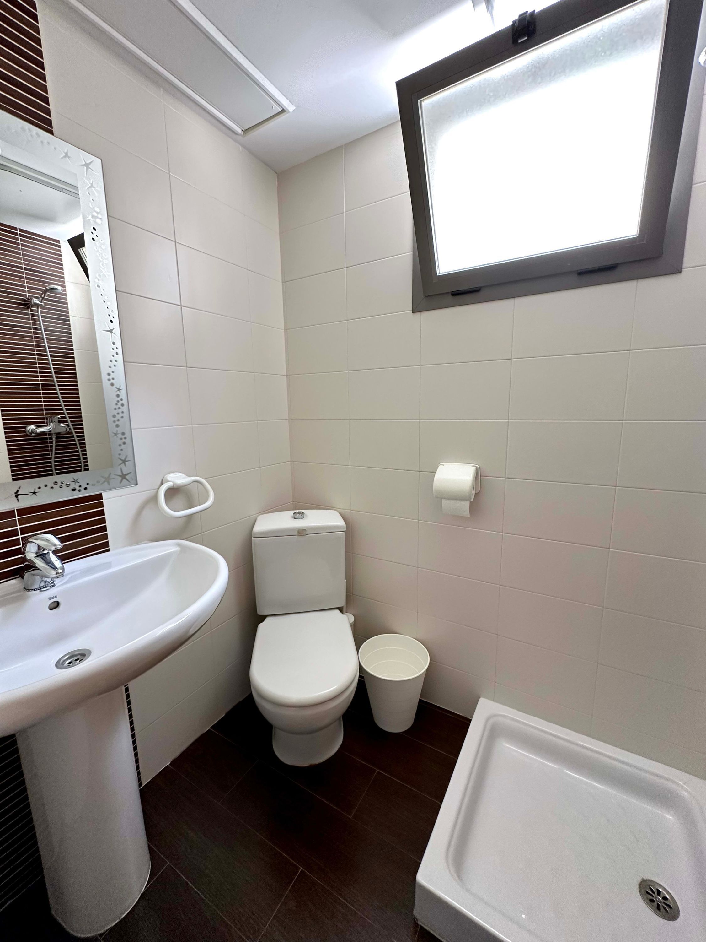 A bathroom with a sink, toilet, and a window.