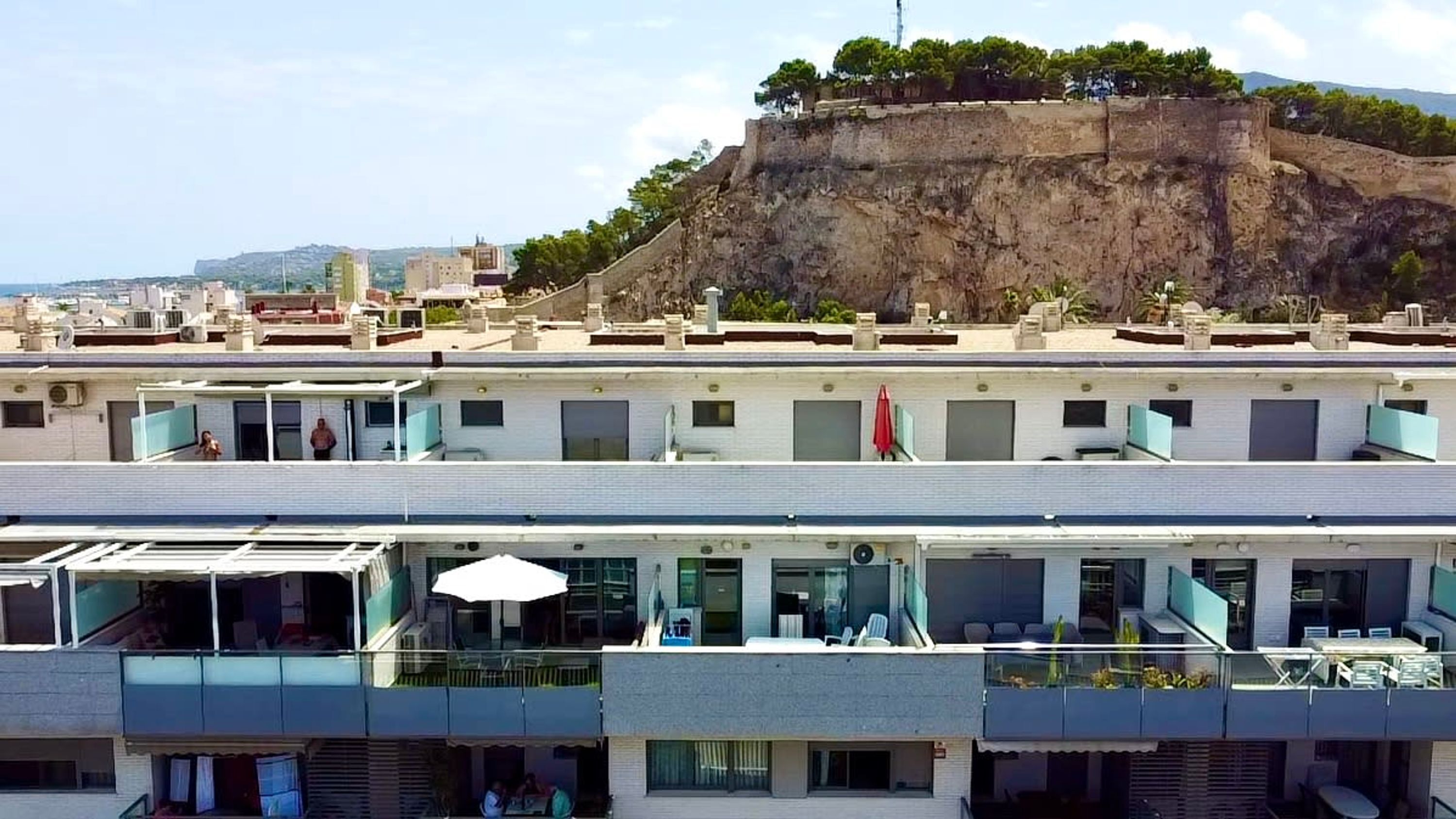 A hotel with multiple floors, balconies, and a view of a historic fort on a hill.