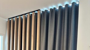 Ein Zimmer mit einer Holzwand und grauen Vorhängen.