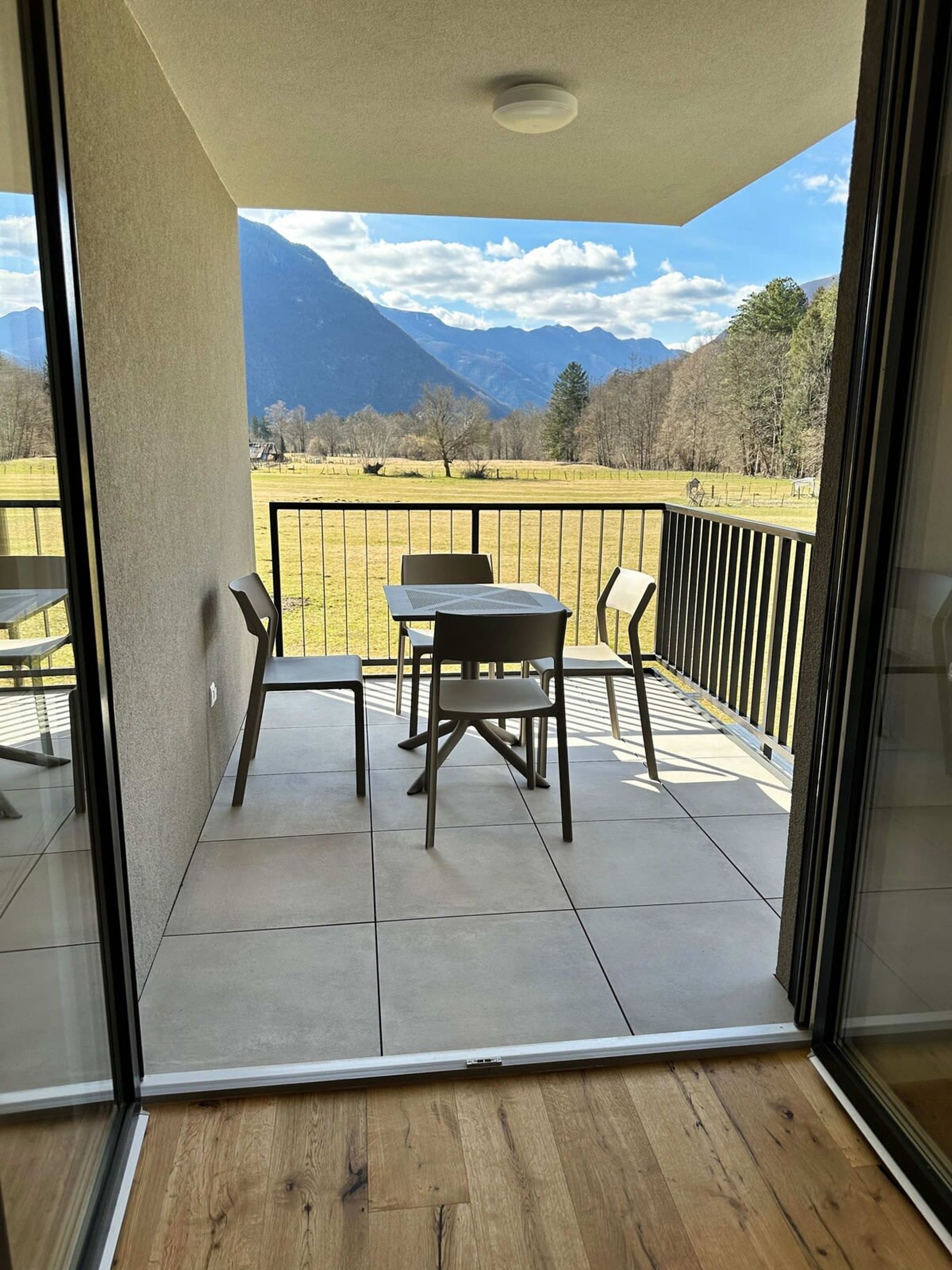 A balcony with a table and chairs, offering a view of a mountainous landscape.