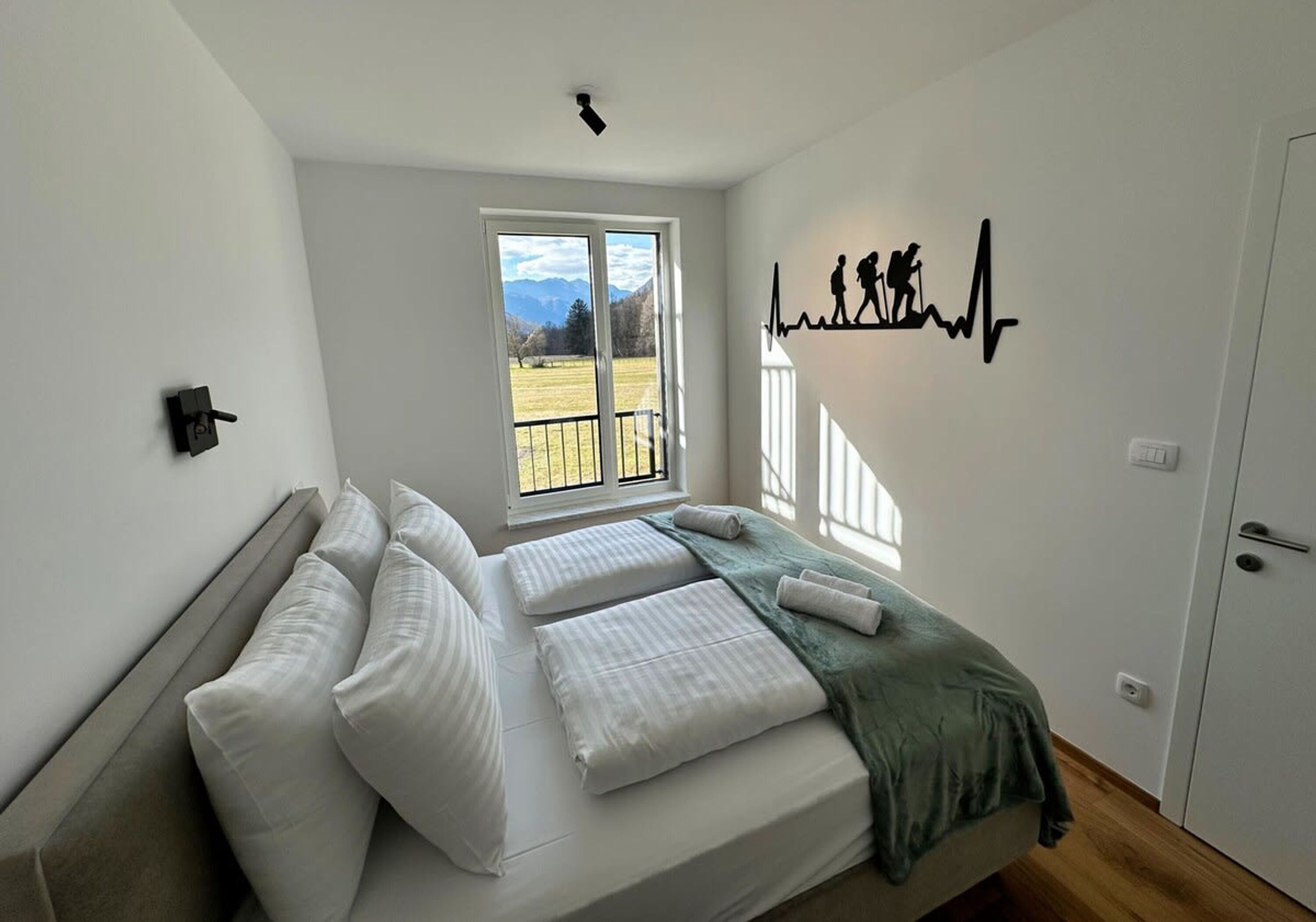 Un dormitorio con cama, ventana, una obra de arte en la pared y una puerta.